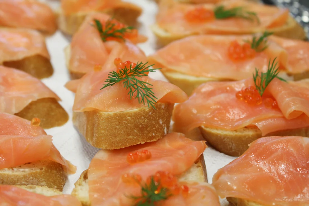 Canapés mit Räucherlachs, rotem Kaviar und Dill auf knusprigen Baguettescheiben, elegant angerichtet.