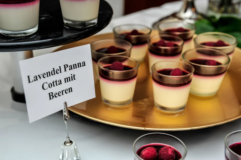 Elegante Präsentation von Lavendel Panna Cotta mit Beeren in Gläsern auf goldenem Teller.